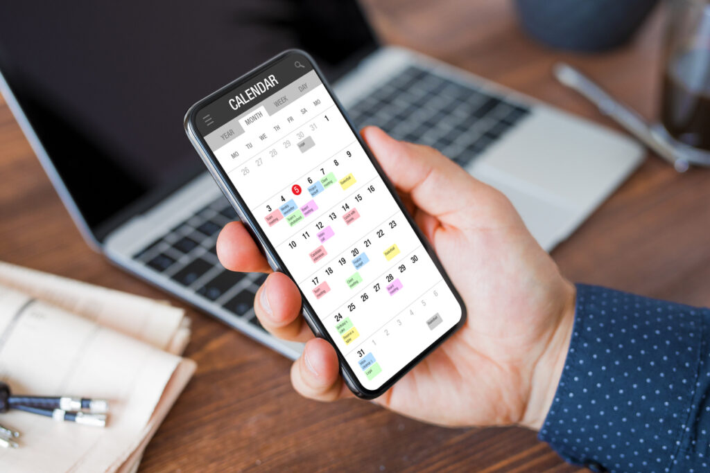 Man using calendar app on mobile phone - At Home With Mackenzie A guy using the calendar app on his phone to plan out the month. A digital planner helps him to get the most out of his planner