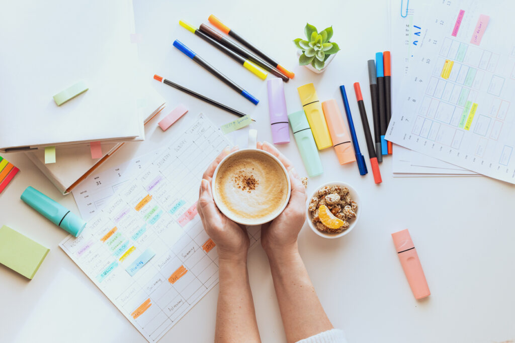 woman planning out her week with cup of coffee - At Home With Mackenzie a woman planning her week with highlighters and colorful pens to get the most out of her planner
