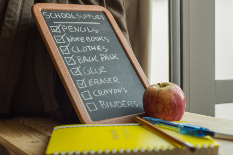 Chalkboard next to backpack with school supplies list
