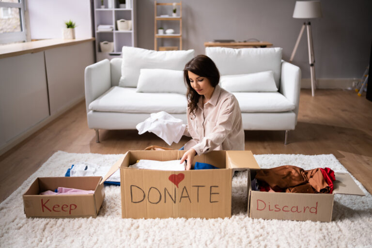 Woman decluttering with donate, discard, and keep boxes in front of her