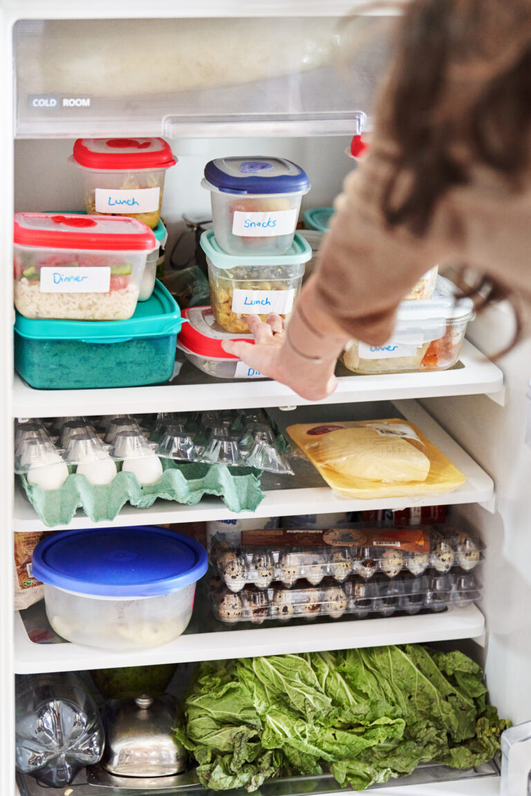 Woman looking at healthy prepared meals in her fridge at home
