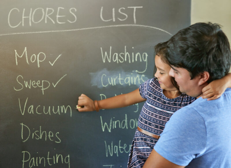 Its been a productive day of chores - At Home With Mackenzie Shot of a father holding his daughter while she marks off chores on a chalkboard